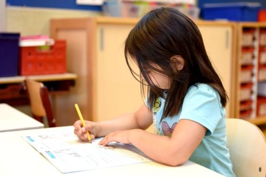 First-grade child tracing letters using phonics-based letter sequence worksheet